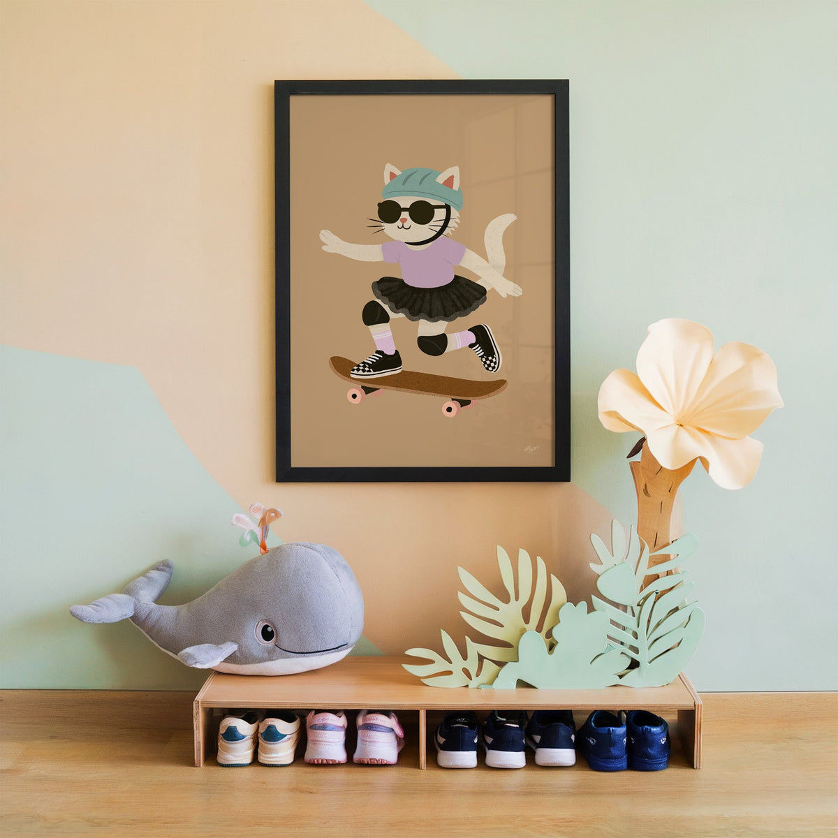 Skater cat in black tutu nursery print in a black frame on a mint and peach wall above a whale plush
