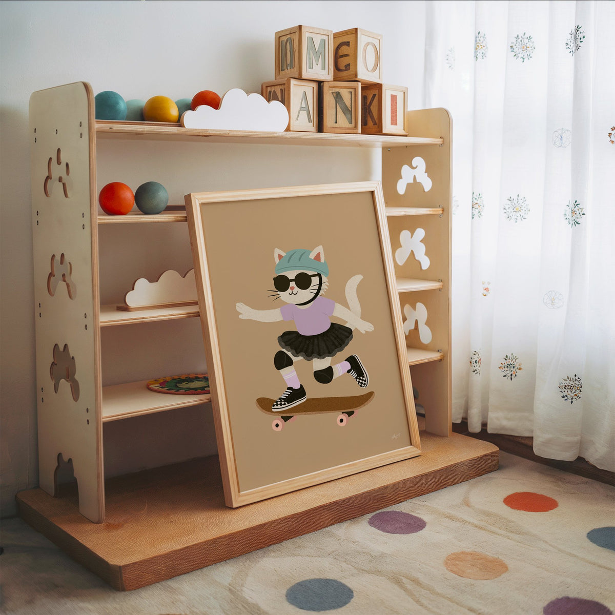 Skater cat in black tutu nursery print in an oak frame leaning on a toy shelf with wooden letter blocks