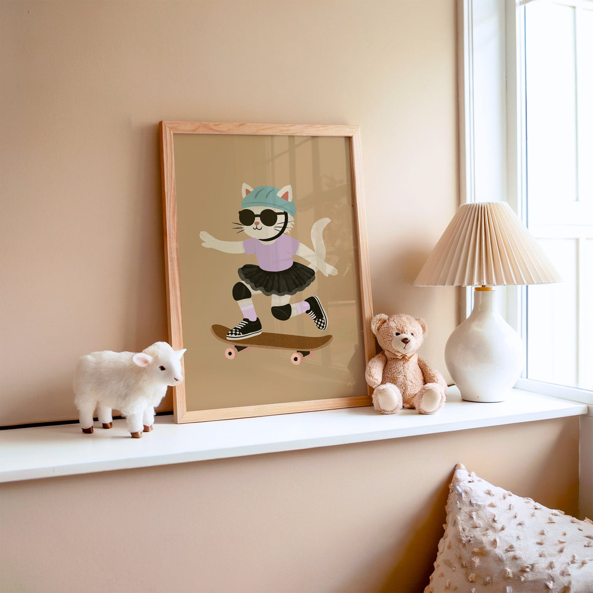 Skater cat in black tutu nursery print in an oak frame on a window ledge with a toy lamb and teddy