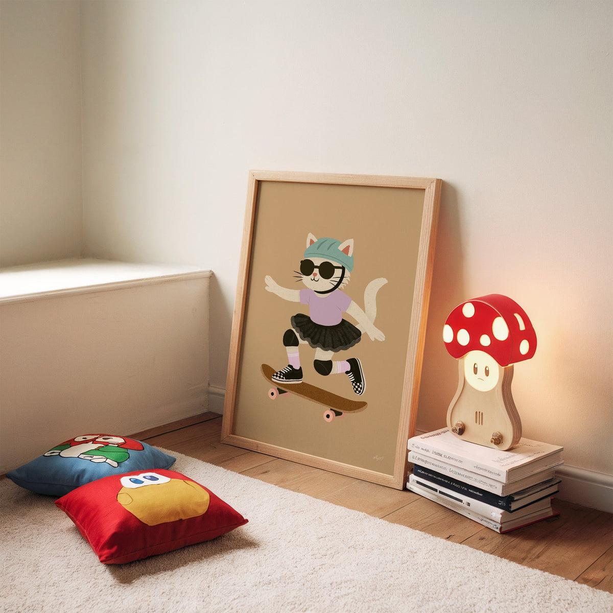Skater cat in black tutu nursery print in an oak frame leaning on a rug beside a mushroom lamp and floor cushions