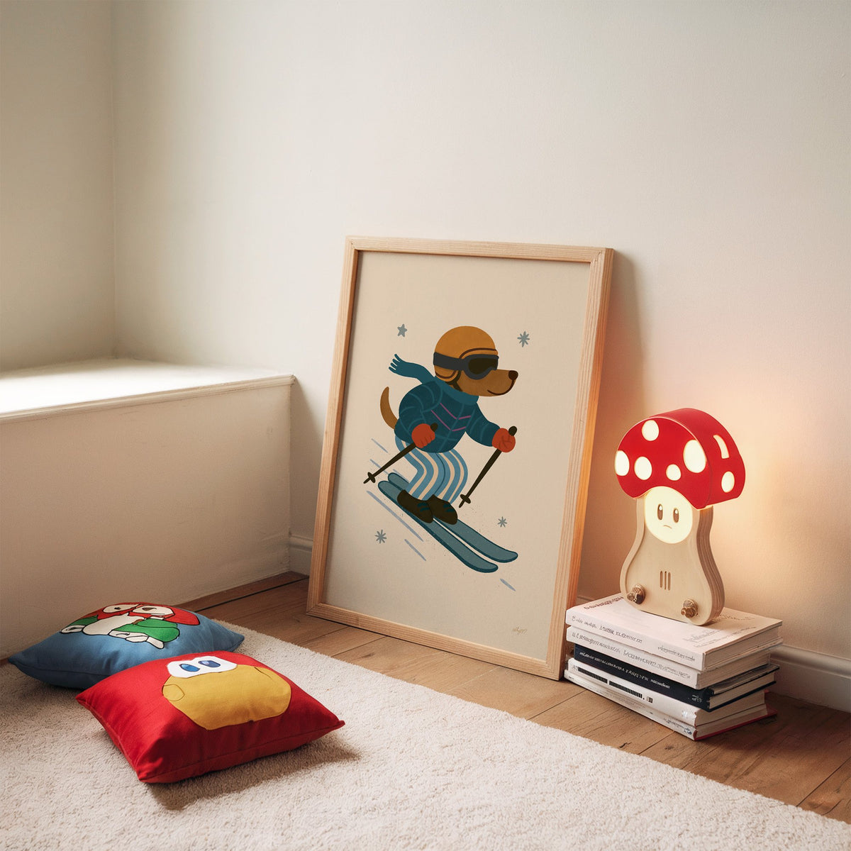 Skiing dog in puffer jacket nursery print in an oak frame leaning on a rug beside a mushroom lamp and floor cushions