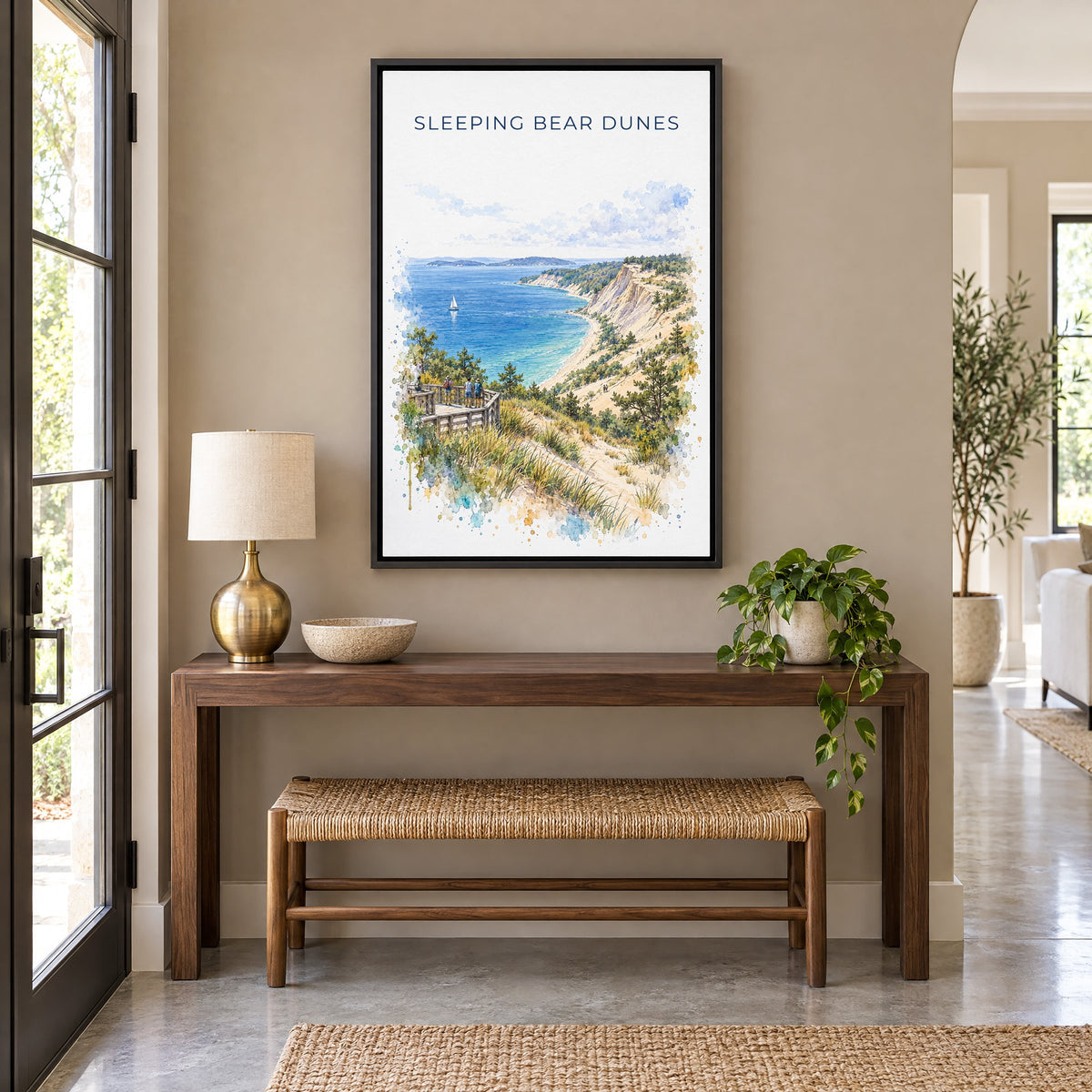 Sleeping Bear Dunes watercolor print as a black floater canvas above a walnut console and woven bench in an entryway