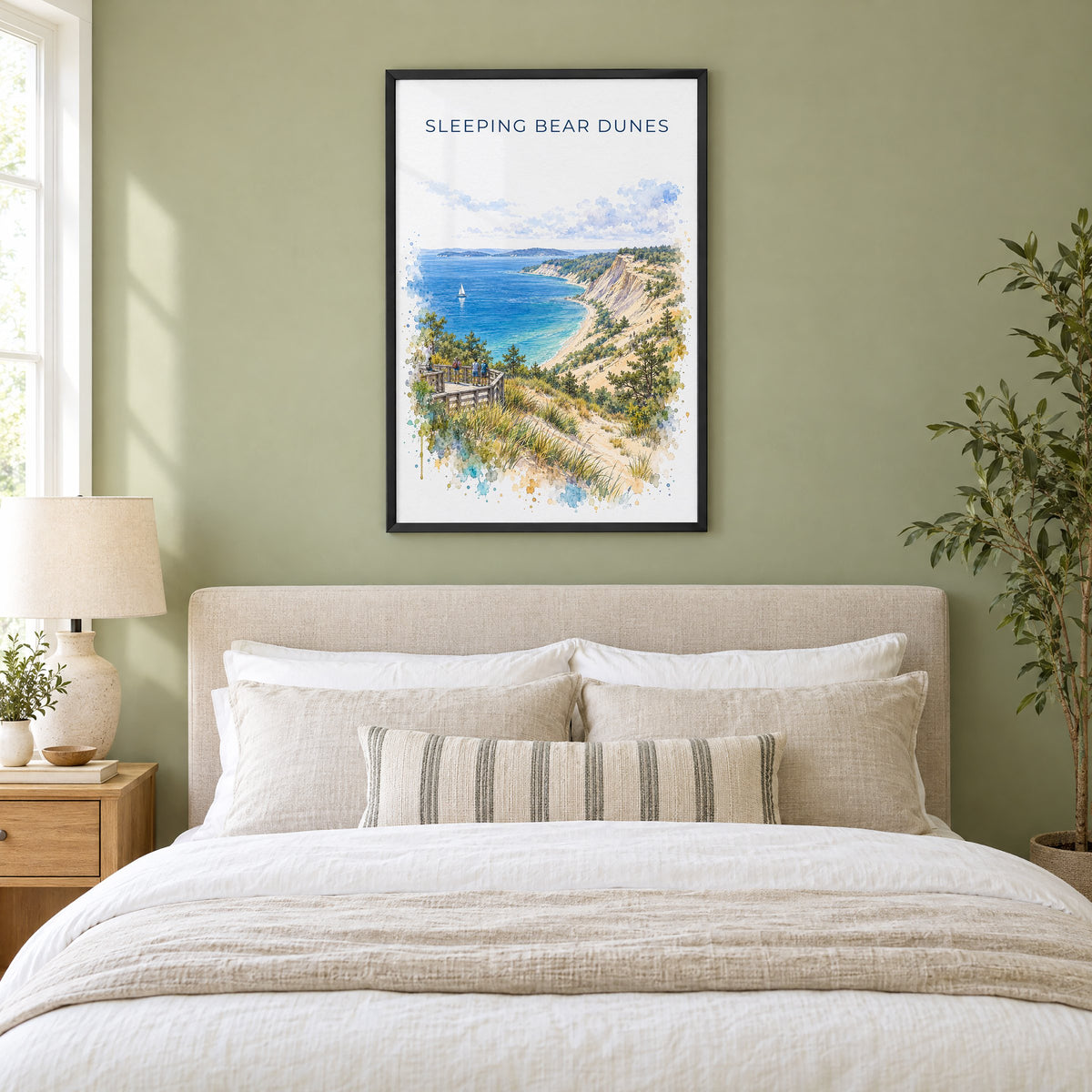 Sleeping Bear Dunes watercolor print in a black frame above an upholstered headboard in a sage green bedroom