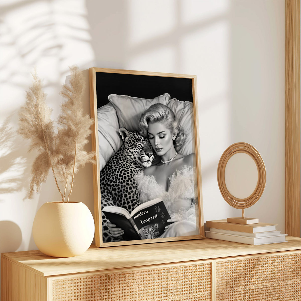 Woman asleep on pillows with leopard and book print in an oak frame on a rattan sideboard beside pampas grass