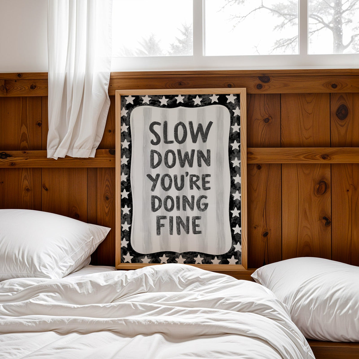 Slow down you're doing fine quote with star border print in a pine frame leaning on a wood headboard over white bedding