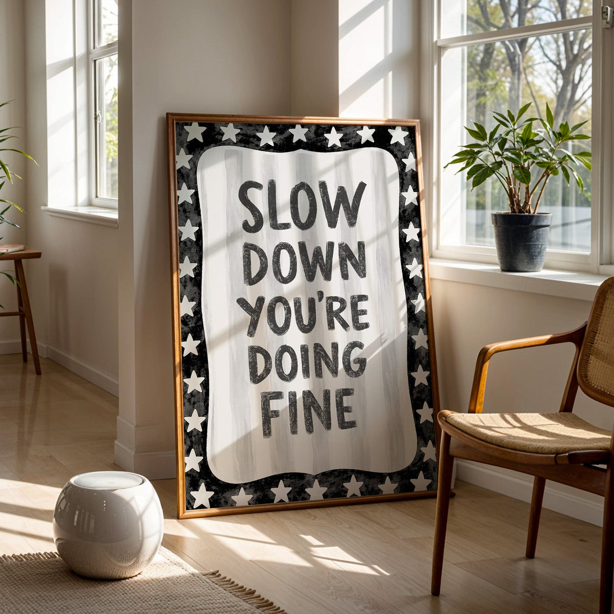 Slow down you're doing fine quote with star border print in a walnut frame on a wood floor beside a cane chair and sunny window