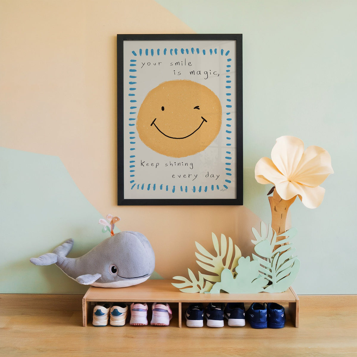 Winking smiley face quote nursery print in a black frame on a mint and peach wall above a whale plush