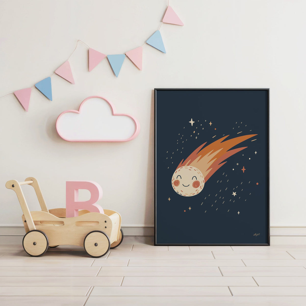 Smiling comet with fiery tail nursery print in a black frame under pastel bunting by a wooden baby walker