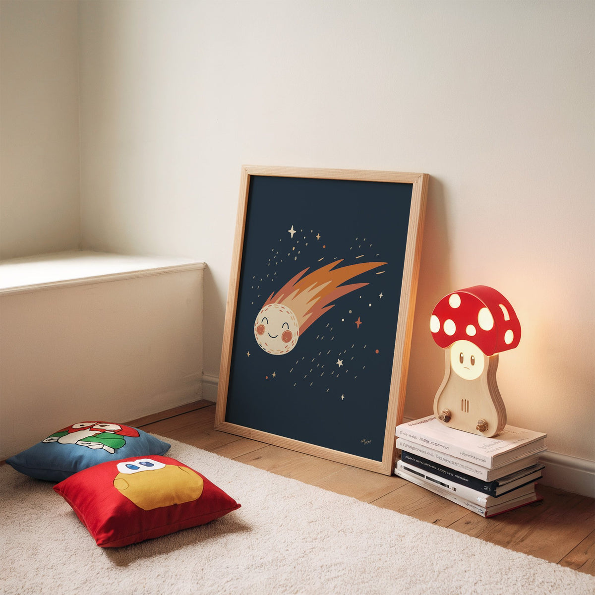 Smiling comet with fiery tail nursery print in an oak frame leaning on a rug beside a mushroom lamp and floor cushions