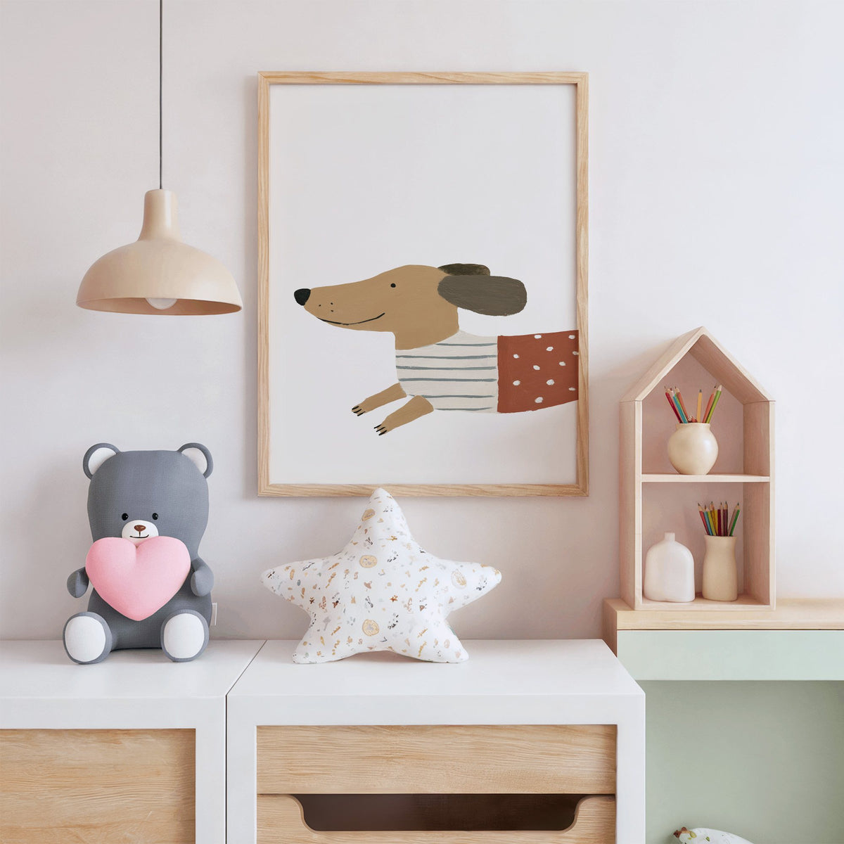 Smiling dachshund close-up nursery print in an oak frame above a white dresser with a star pillow and house shelf