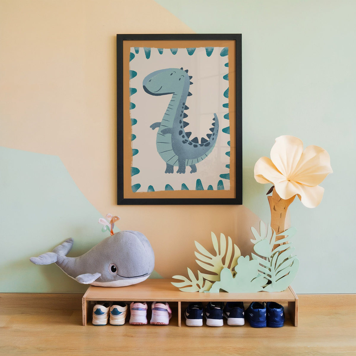 Smiling teal dinosaur nursery print in a black frame on a mint and peach wall above a whale plush