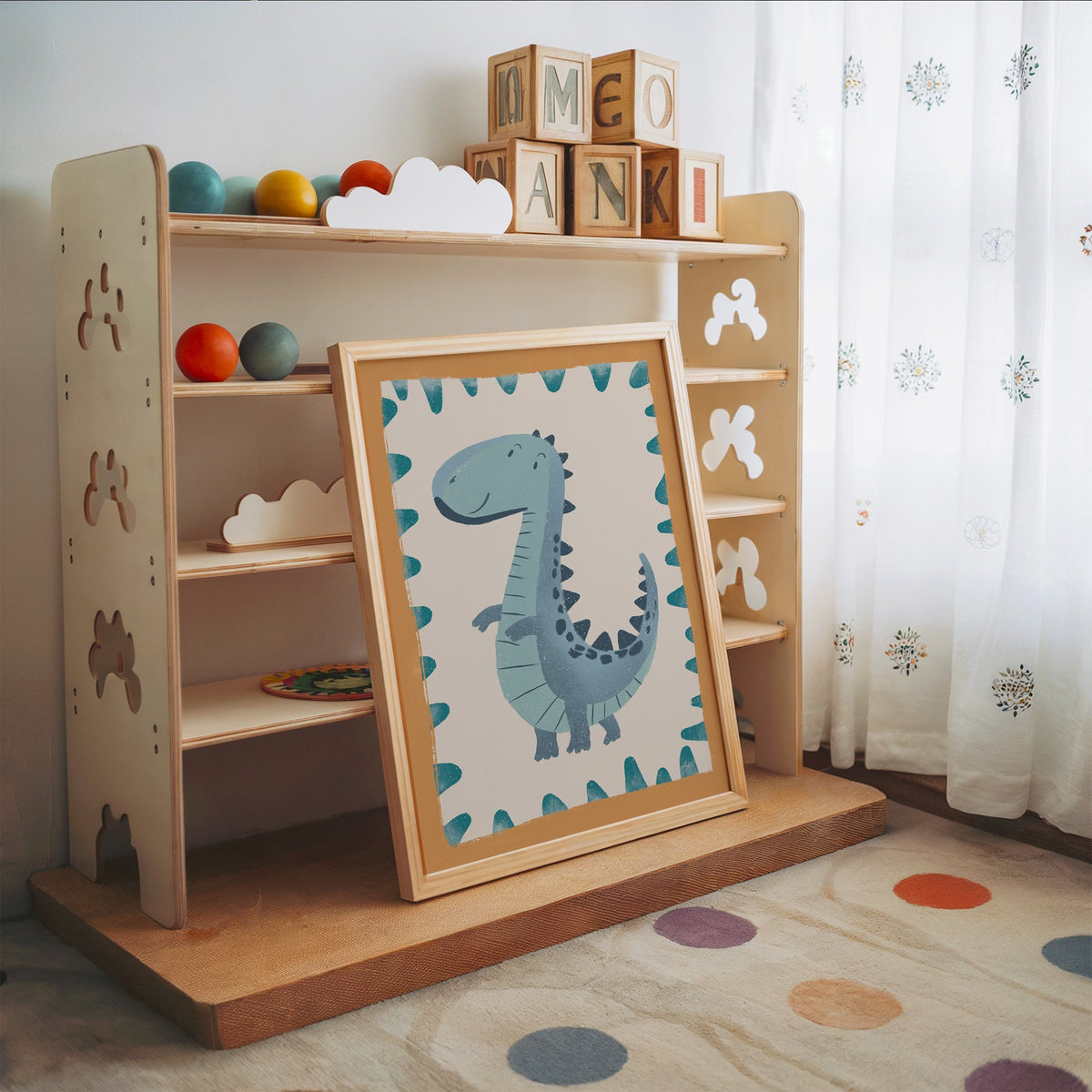 Smiling teal dinosaur nursery print in an oak frame leaning on a toy shelf with wooden letter blocks