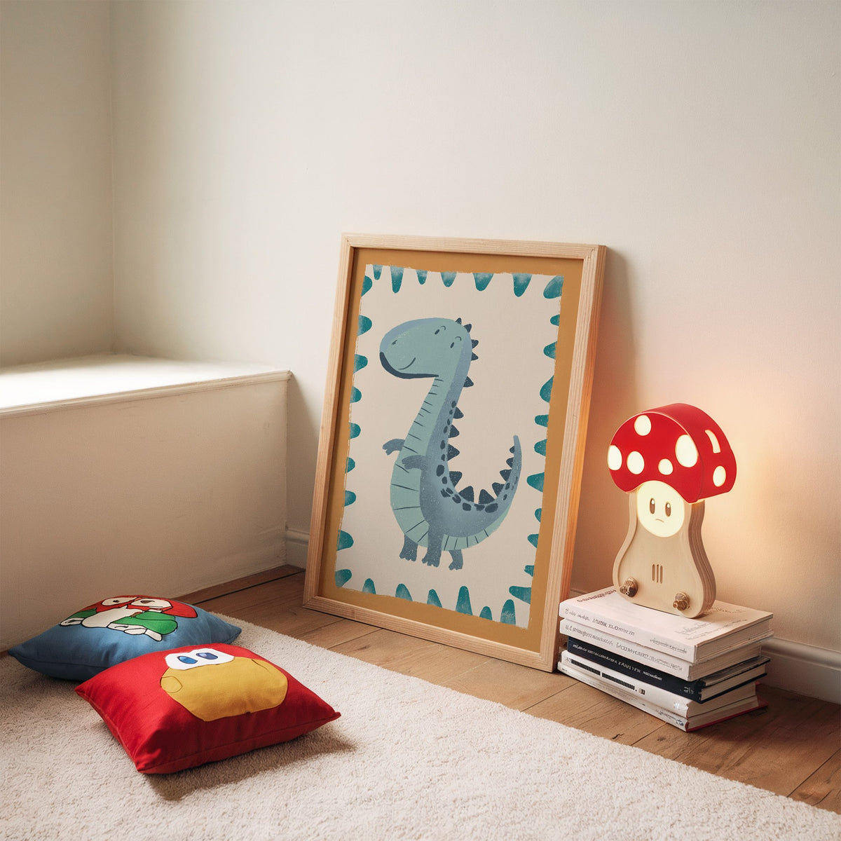 Smiling teal dinosaur nursery print in an oak frame leaning on a rug beside a mushroom lamp and floor cushions