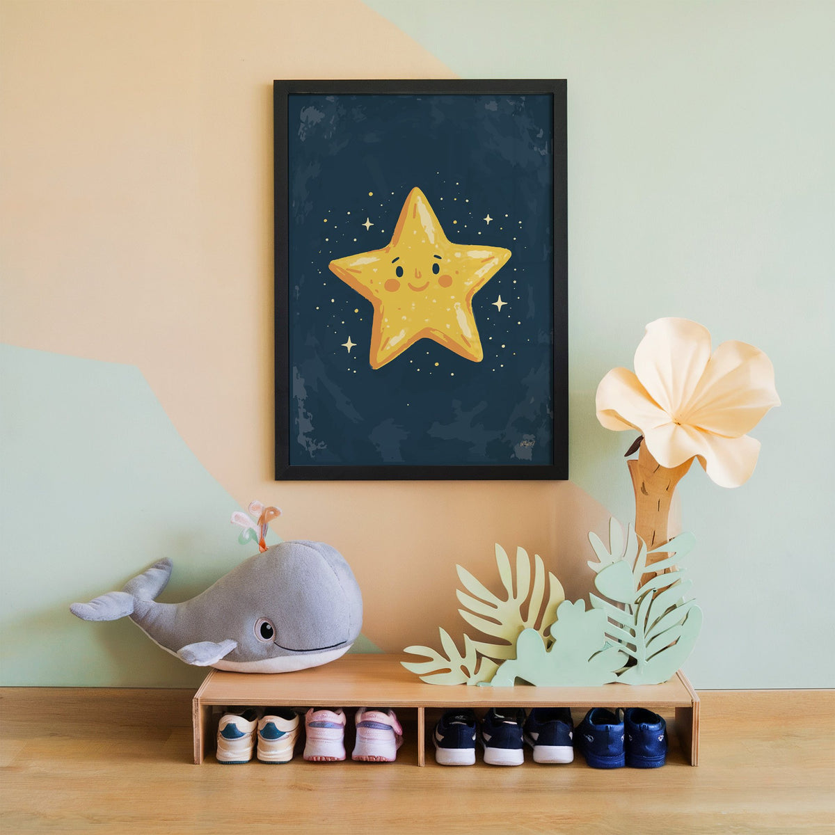 Smiling yellow star on navy nursery print in a black frame on a mint and peach wall above a whale plush