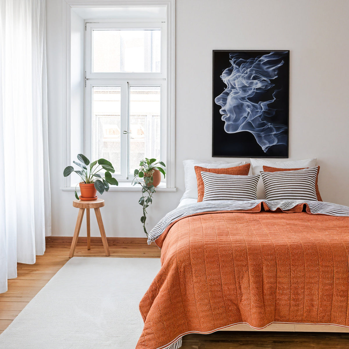 Smoke face profile surreal portrait print in a thin black frame above a bed with a rust orange quilt