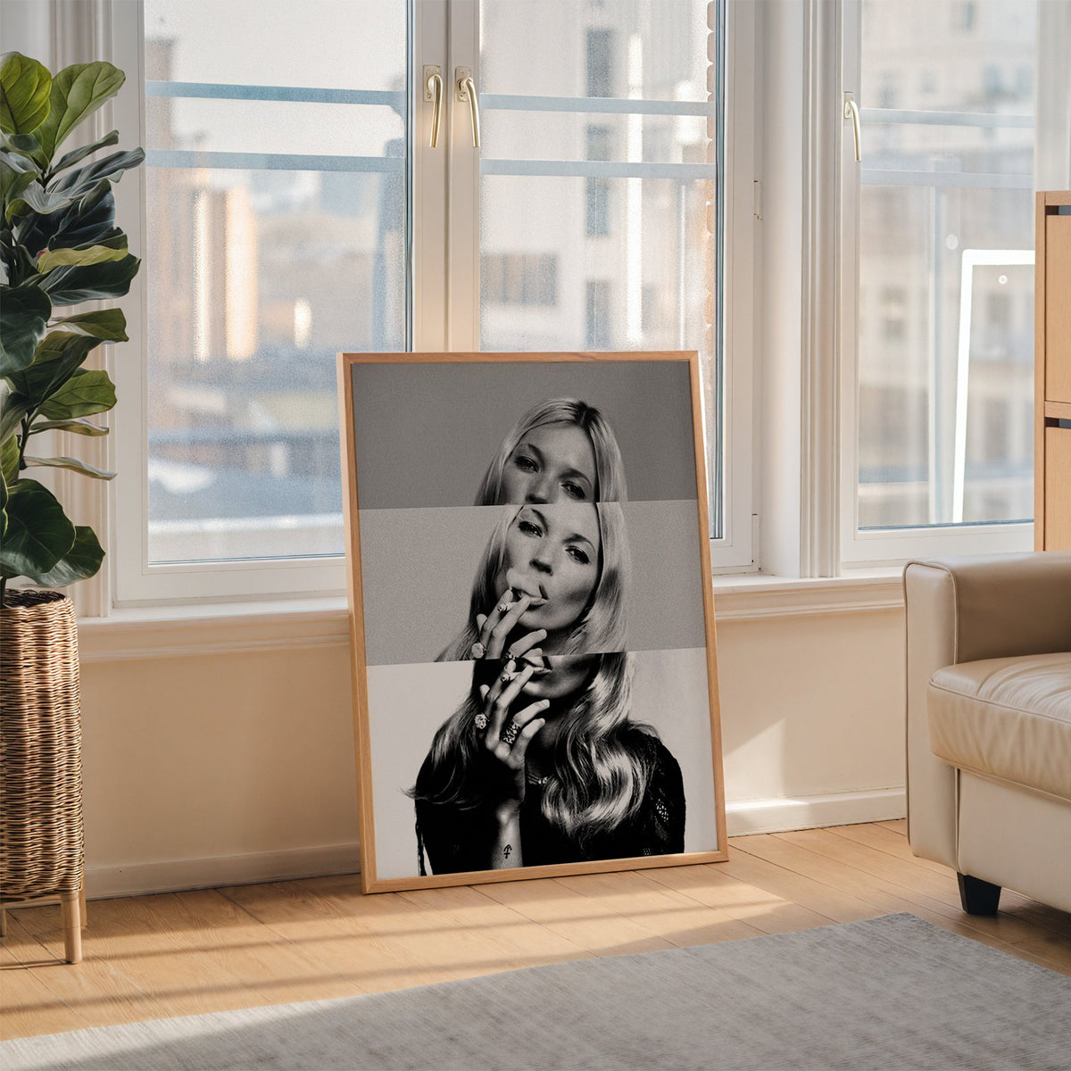 Sliced black and white smoking woman portrait print in an oak frame leaning on the floor beside a fiddle leaf fig