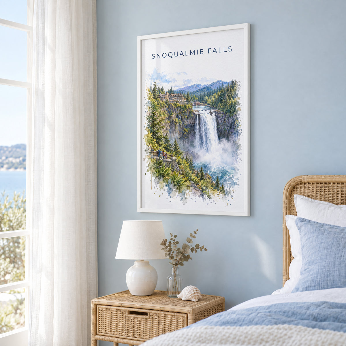Snoqualmie Falls watercolor print in a white frame on a pale blue wall beside a rattan bed in a coastal bedroom