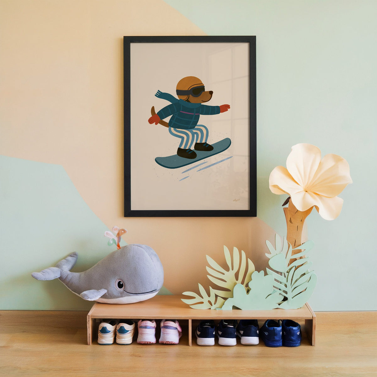 Snowboarding dog with arms wide nursery print in a black frame on a mint and peach wall above a whale plush