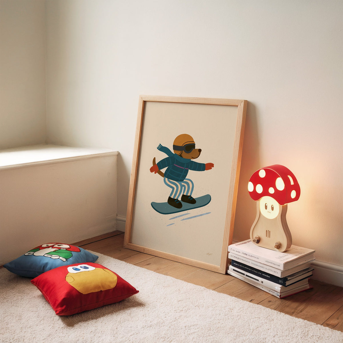 Snowboarding dog with arms wide nursery print in an oak frame leaning on a rug beside a mushroom lamp and floor cushions