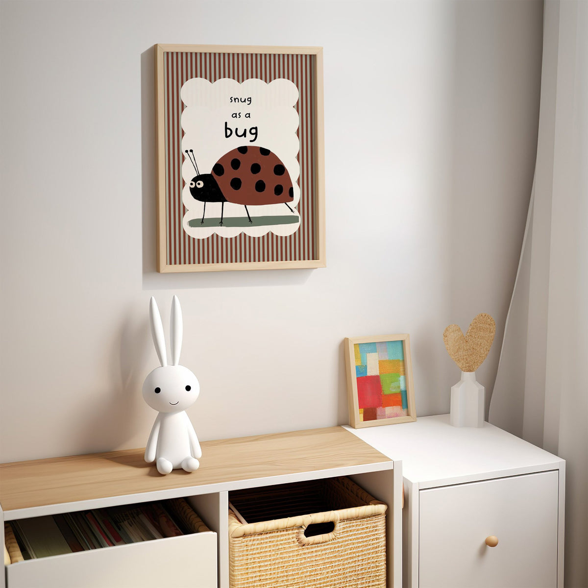 Snug as a bug ladybug nursery print in an oak frame above a kids cubby shelf with a woven basket and bunny lamp