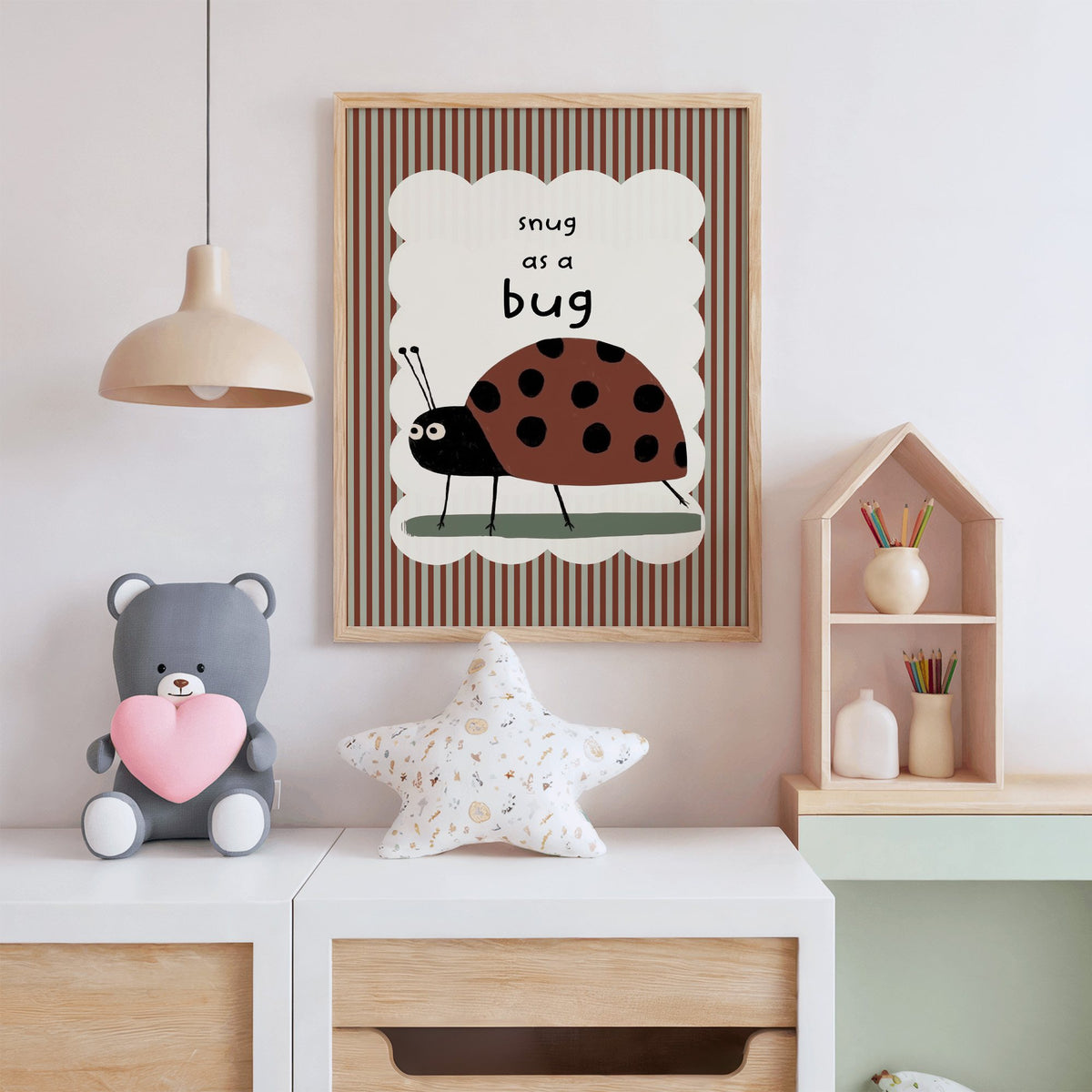 Snug as a bug ladybug nursery print in an oak frame above a white dresser with a star pillow and house shelf