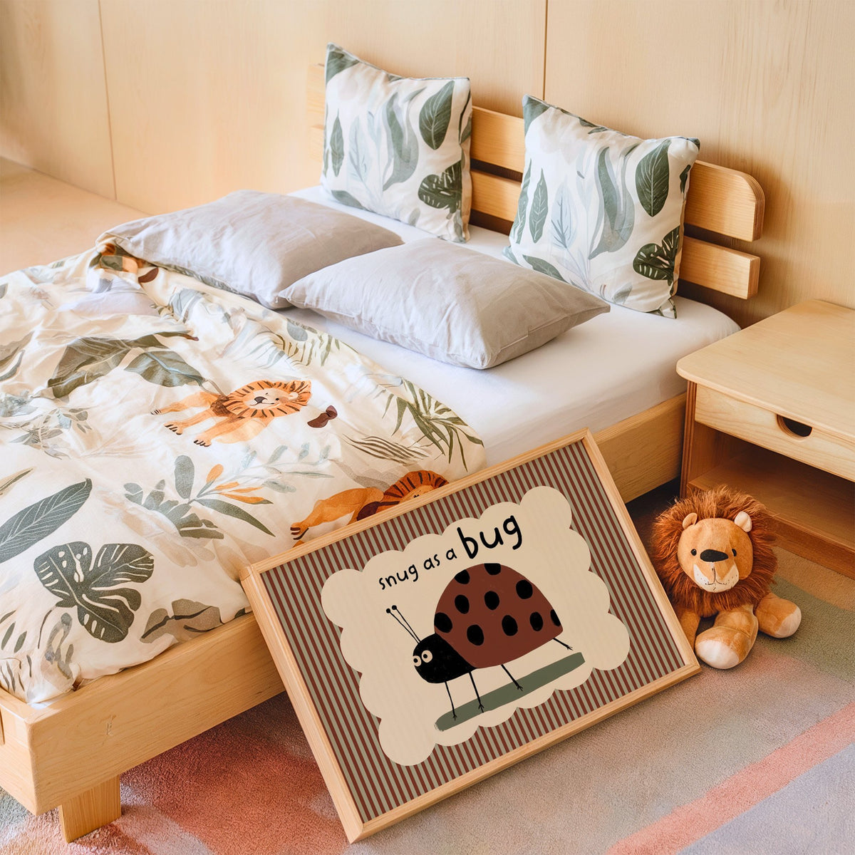 Landscape snug as a bug ladybug nursery print in an oak frame leaning on a kids bed by a lion plush