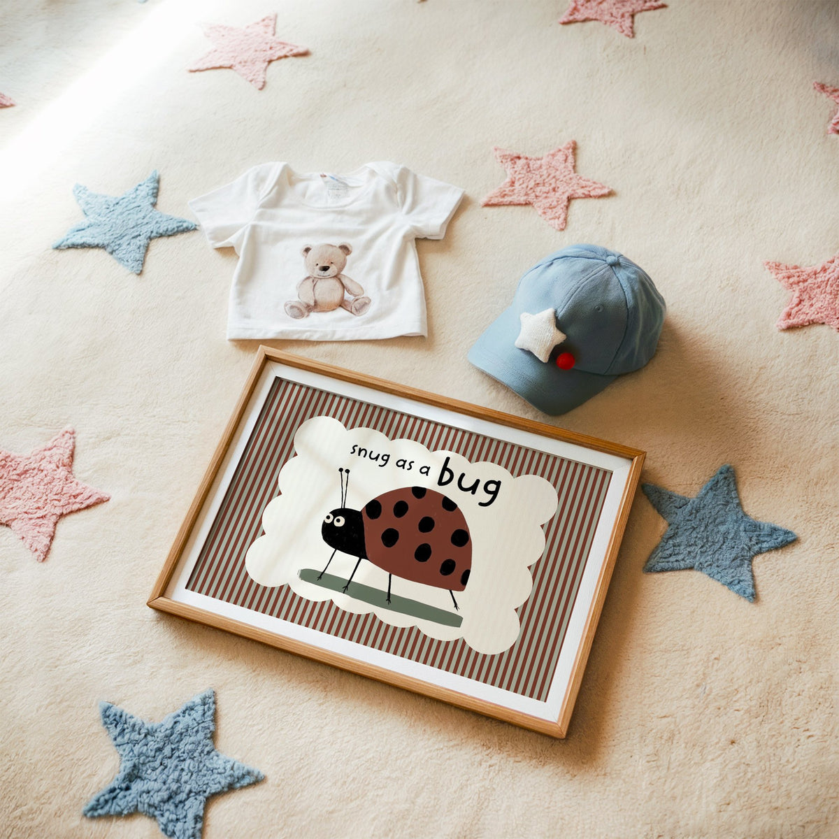 Landscape snug as a bug ladybug nursery print in a matted oak frame on a star rug with a baby tee