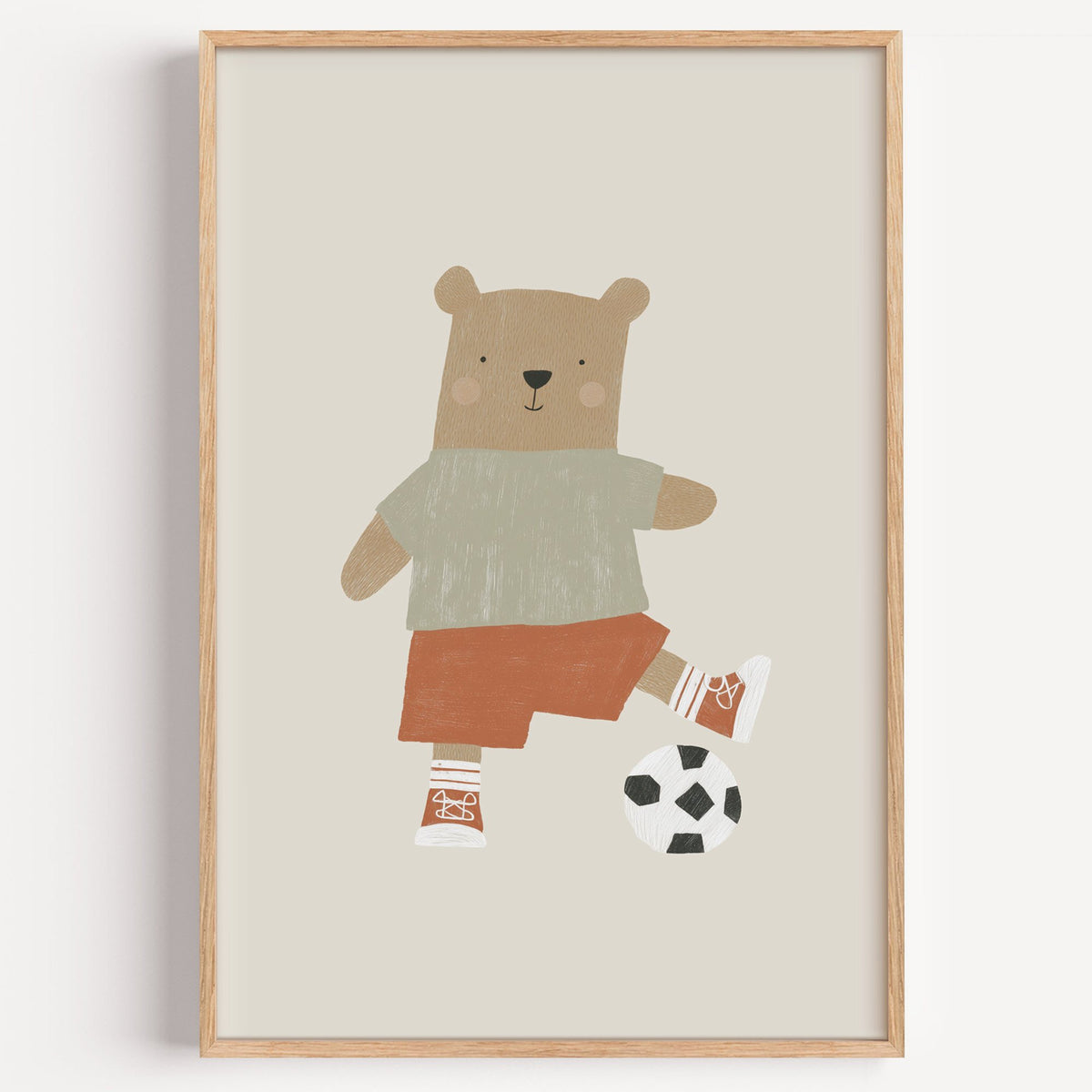 Soccer bear orange shorts nursery print in a light oak frame on a plain white wall