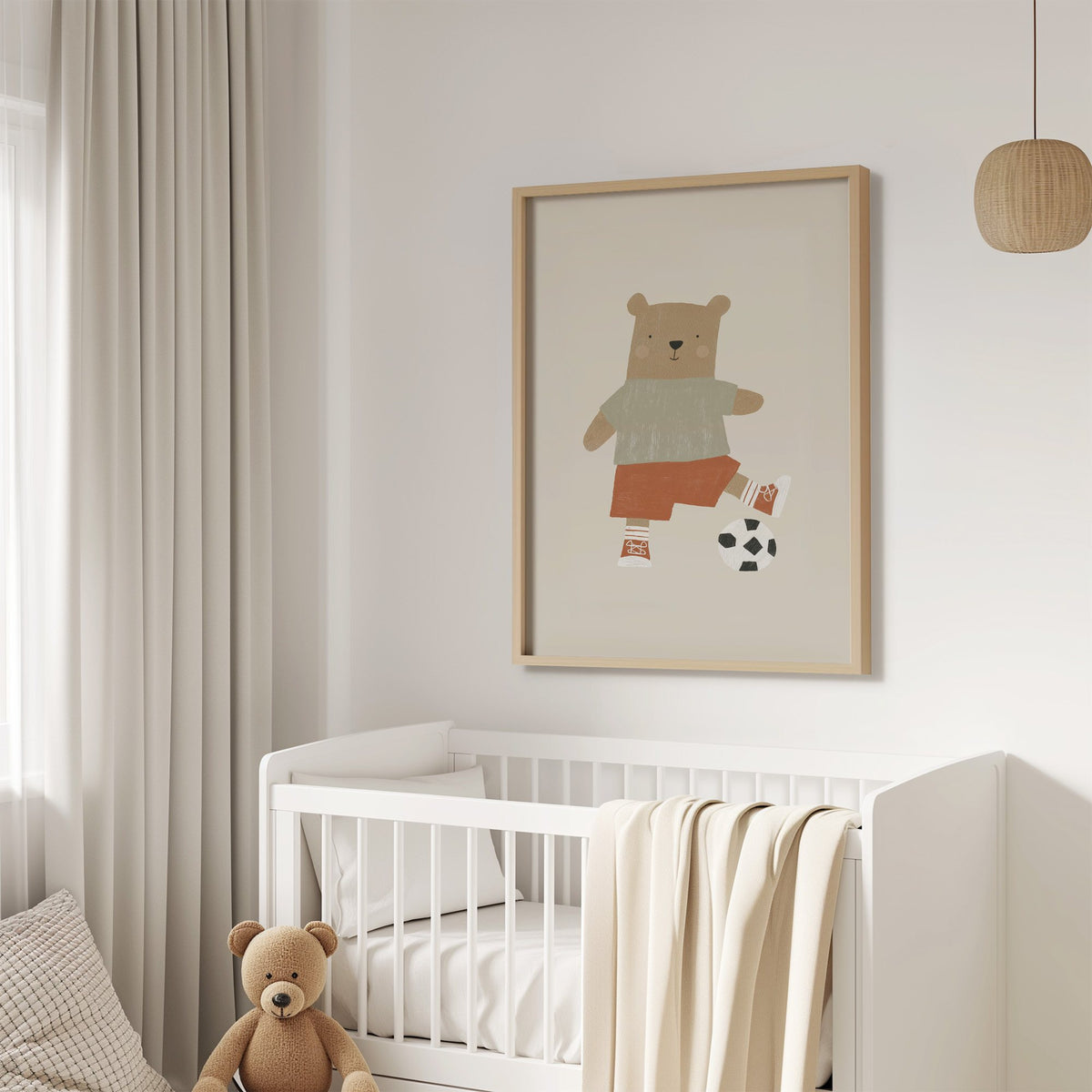 Soccer bear orange shorts nursery print in an oak frame above a white crib with a teddy bear