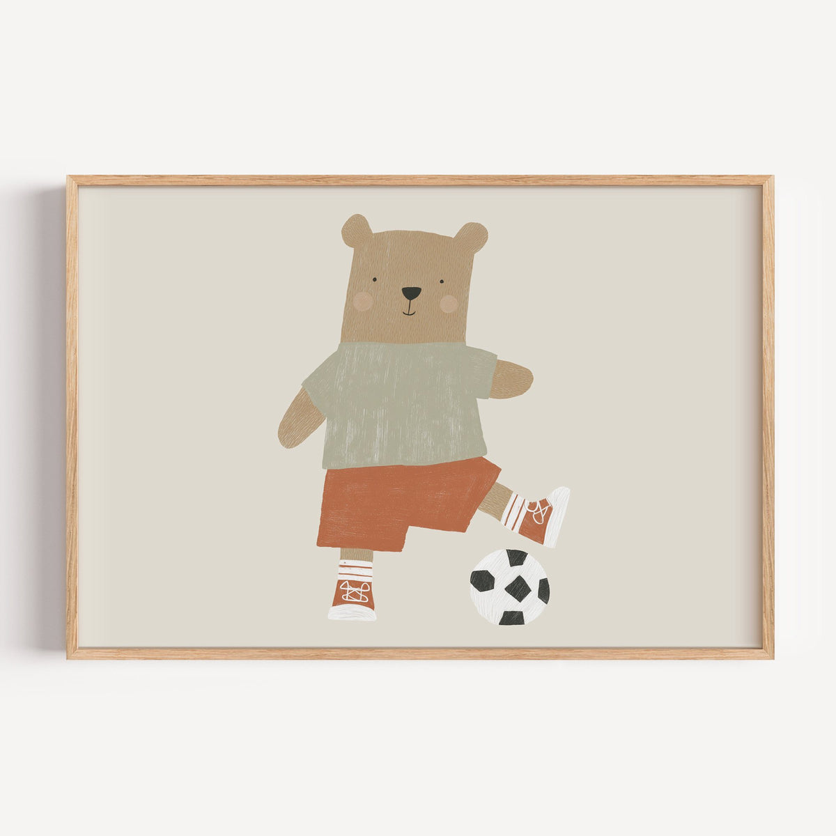 Landscape soccer bear orange shorts nursery print in a light oak frame on a plain white wall