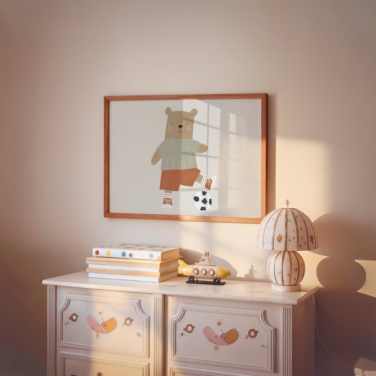 Landscape soccer bear orange shorts nursery print in a cherry wood frame above a painted dresser and lamp