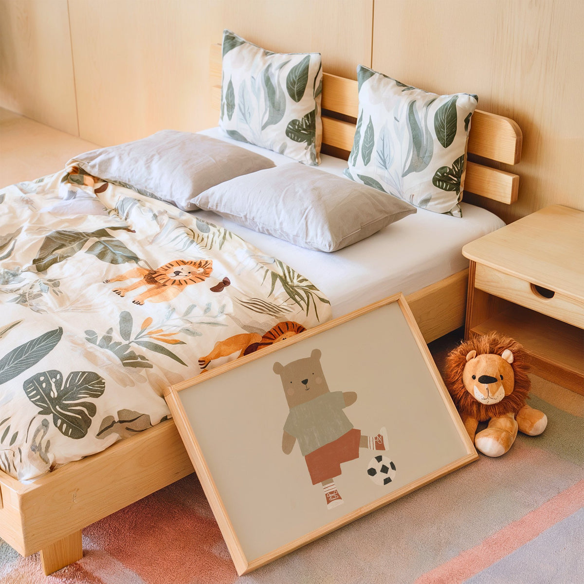 Landscape soccer bear orange shorts nursery print in an oak frame leaning on a kids bed by a lion plush