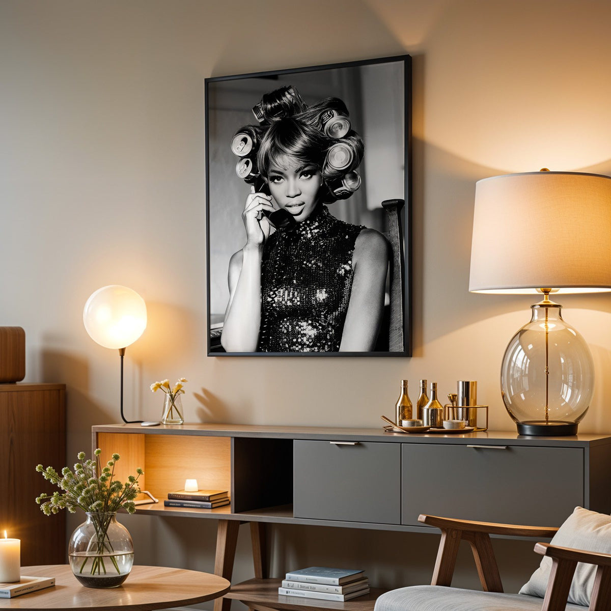 Woman with soda can hair rollers on telephone print in a black frame above a grey media console with a glass table lamp