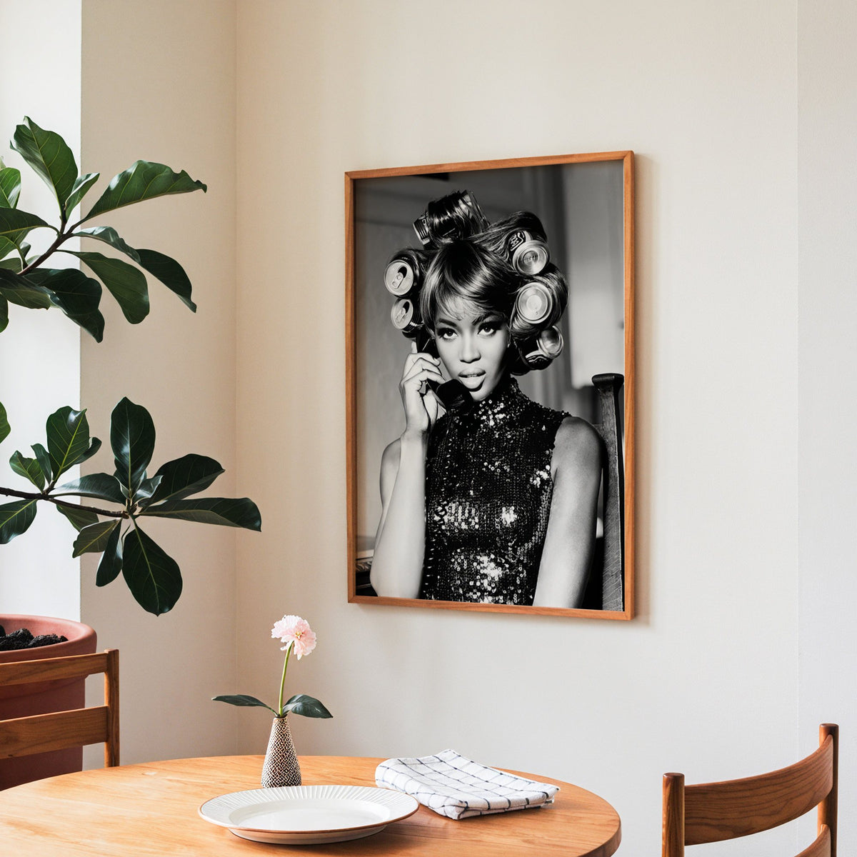 Woman with soda can hair rollers on telephone print in a teak frame above a round wooden dining table