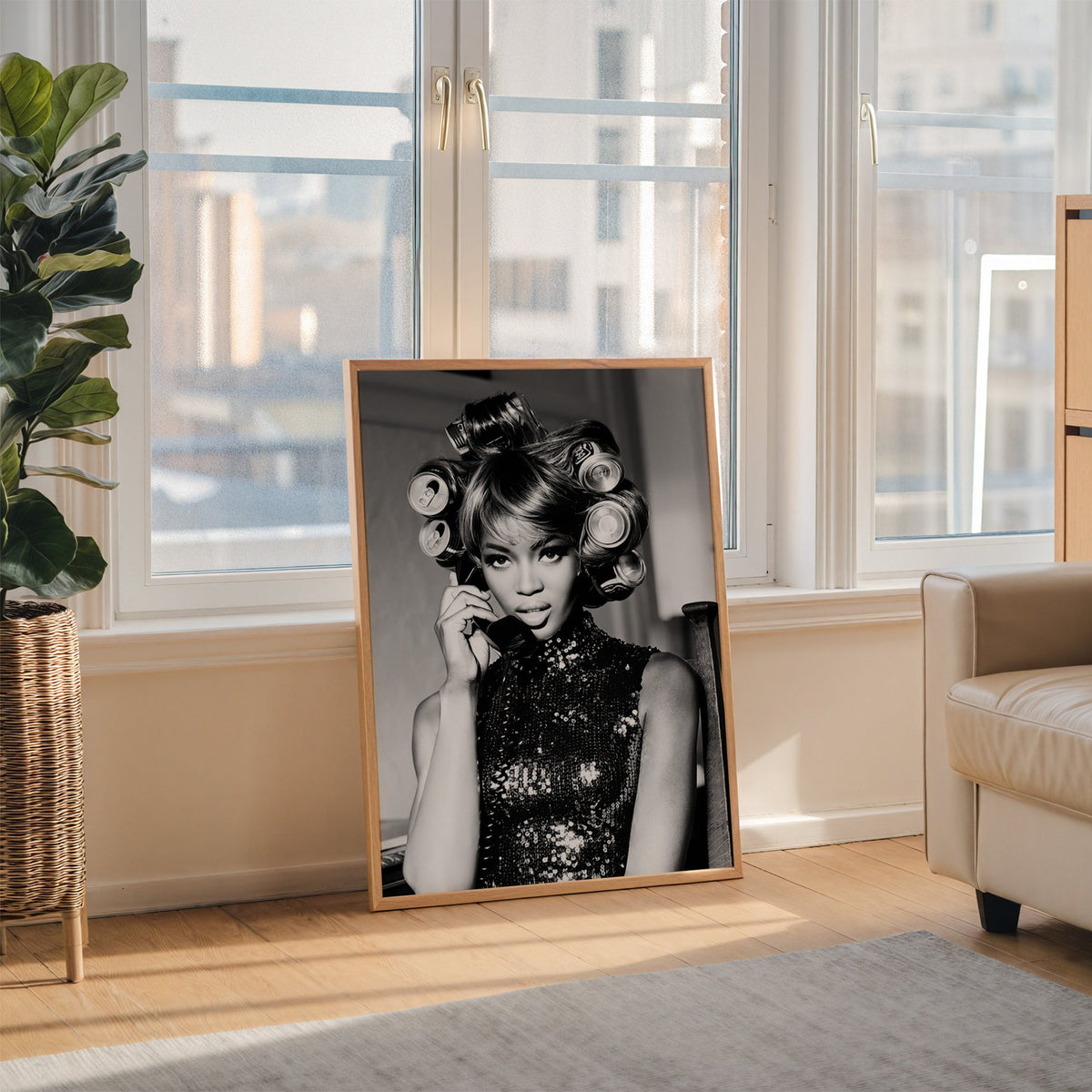 Woman with soda can hair rollers on telephone print in an oak frame leaning on the floor beside a fiddle leaf fig