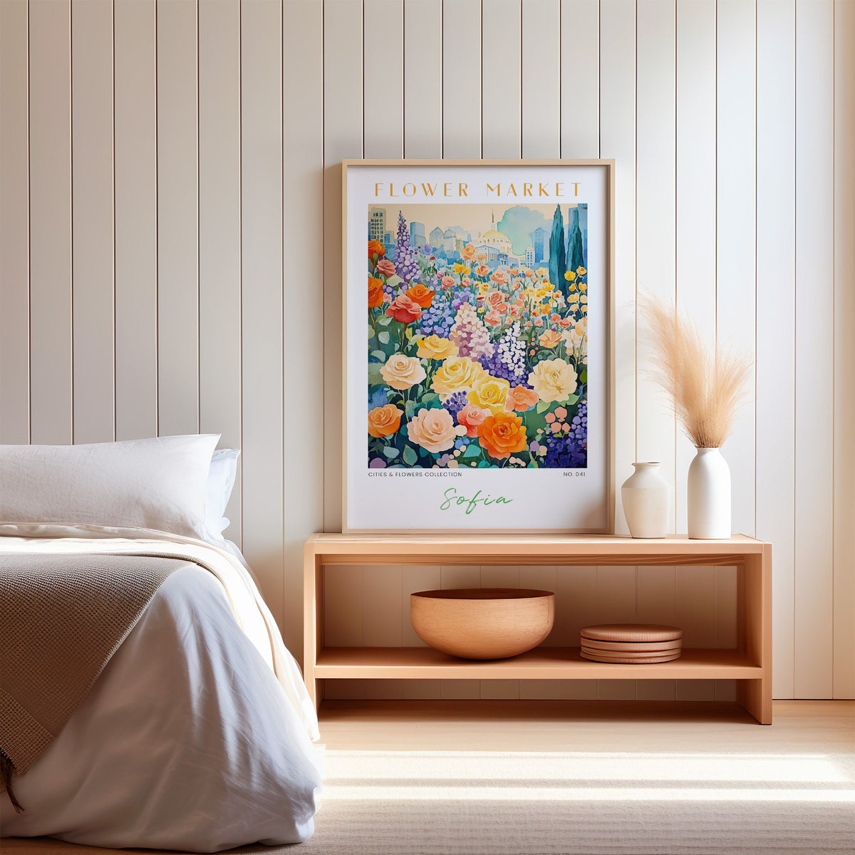 Sofia flower market print in an oak frame on a wood bench against a white shiplap bedroom wall with pampas grass