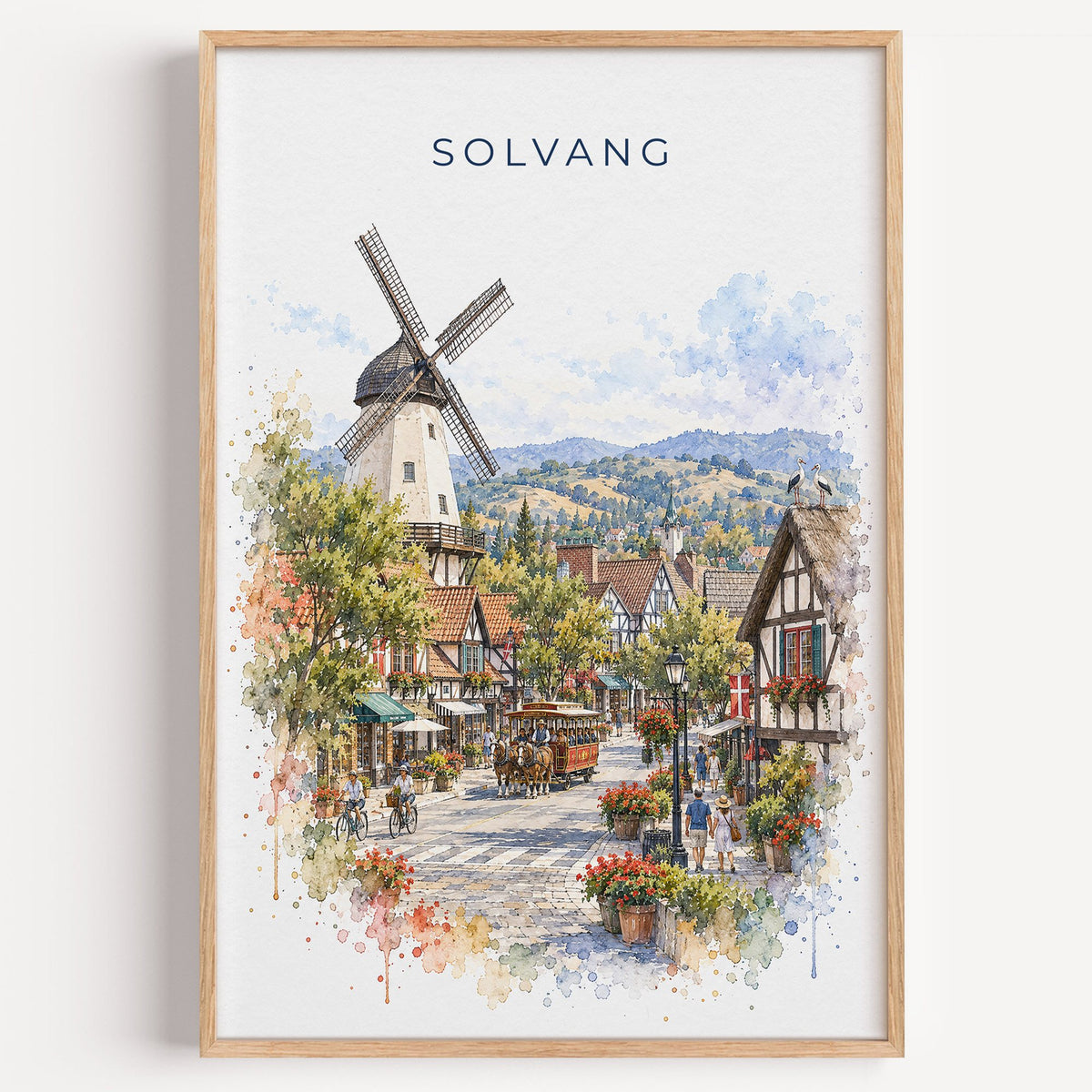 Solvang watercolor print in a light oak frame on a plain white wall