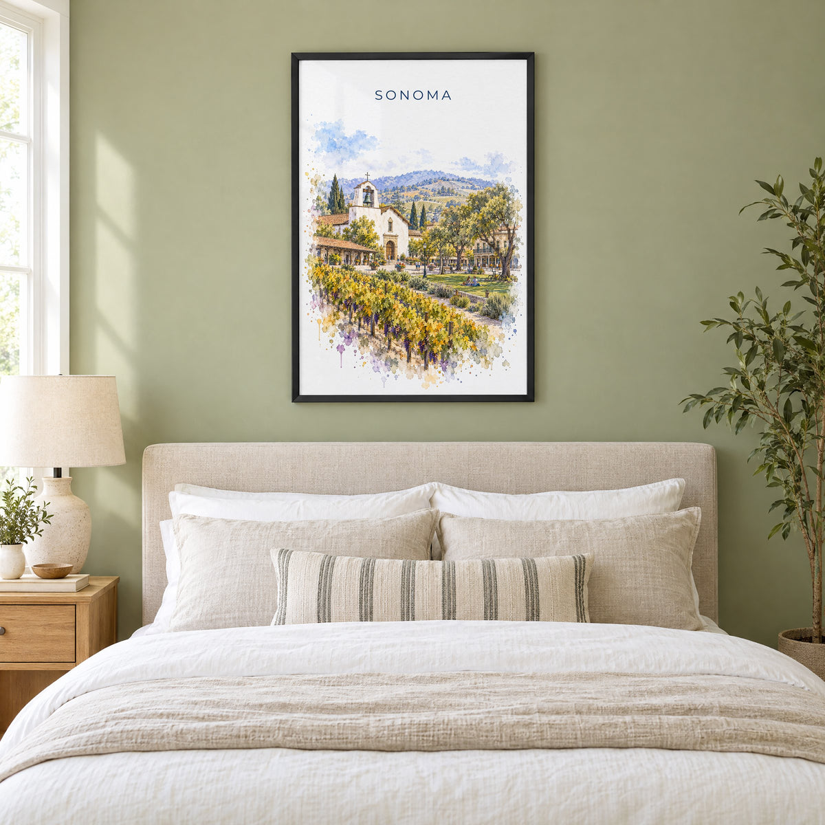 Sonoma watercolor print in a black frame above an upholstered headboard in a sage green bedroom