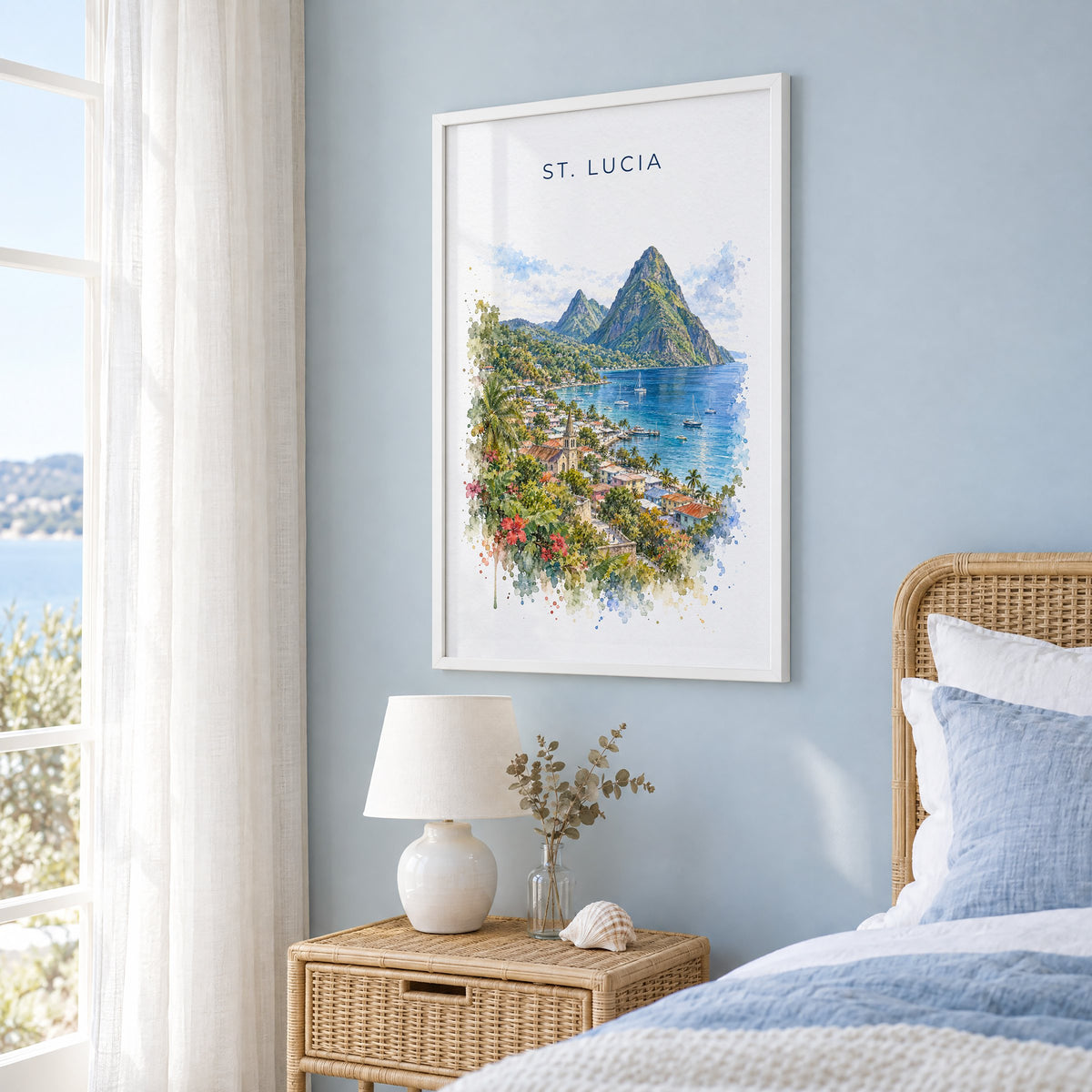 Saint Lucia Pitons watercolor print in a white frame on a pale blue wall beside a rattan bed in a coastal bedroom
