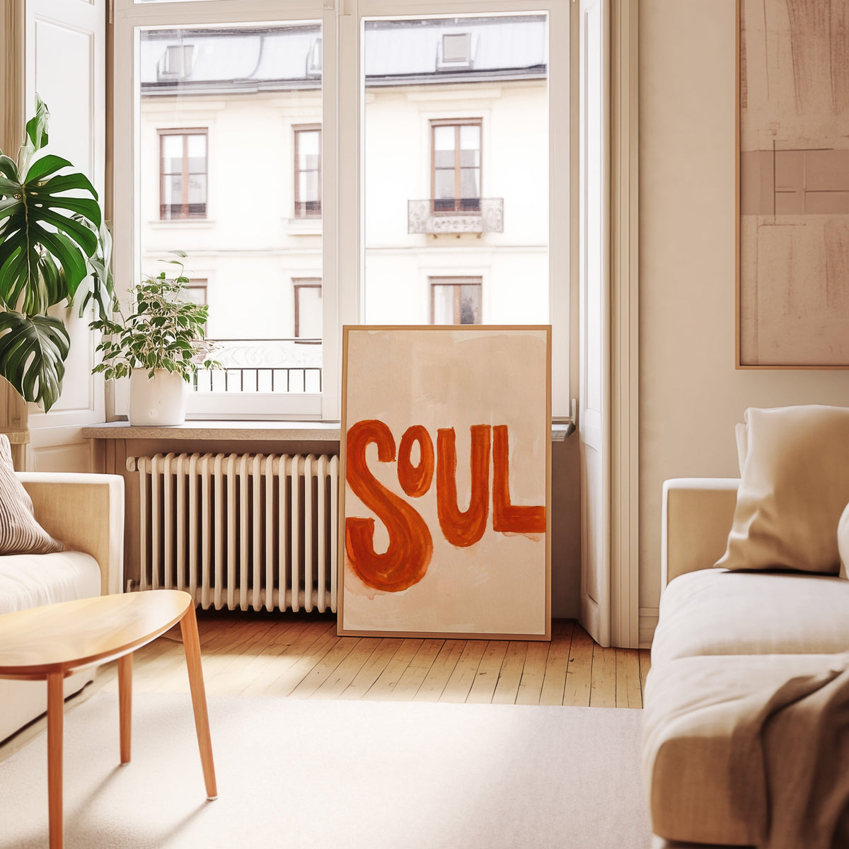 Burnt orange word art print in an oak frame leaning below tall French windows