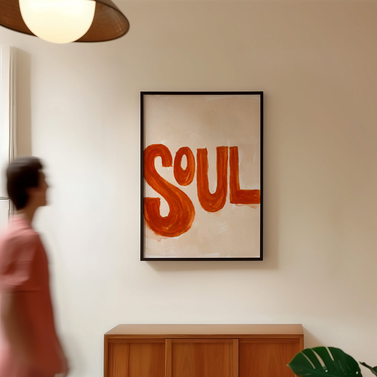 Soul brush lettering print in a black frame in a hallway under a rattan pendant