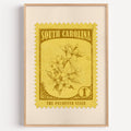 South Carolina state flower stamp print in olive gold on pale yellow, light oak frame on a white wall