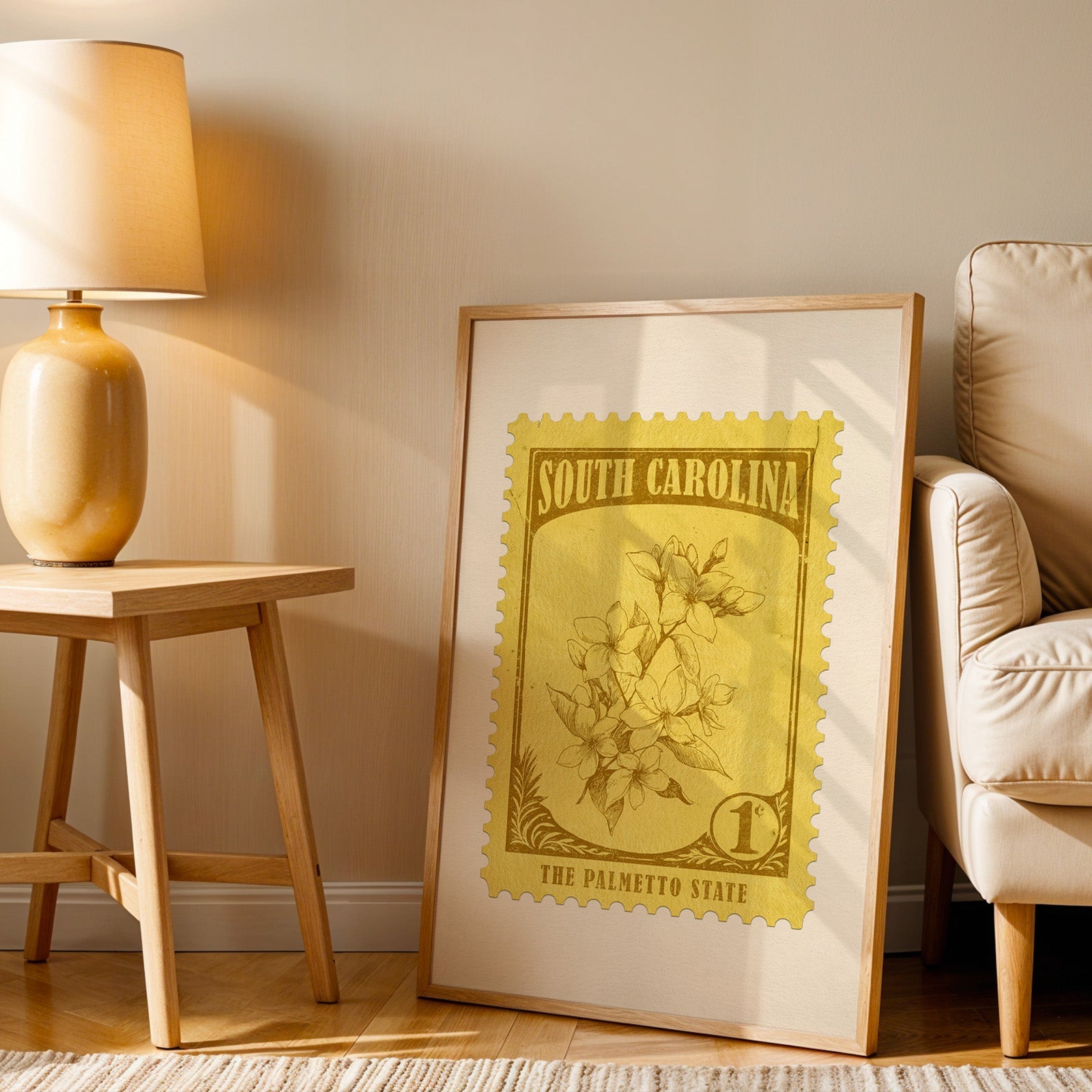 South Carolina stamp print in a wood frame resting on the floor beside a beige armchair and a yellow lamp