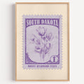 South Dakota state flower stamp print in violet purple on lilac, light oak frame on a white wall