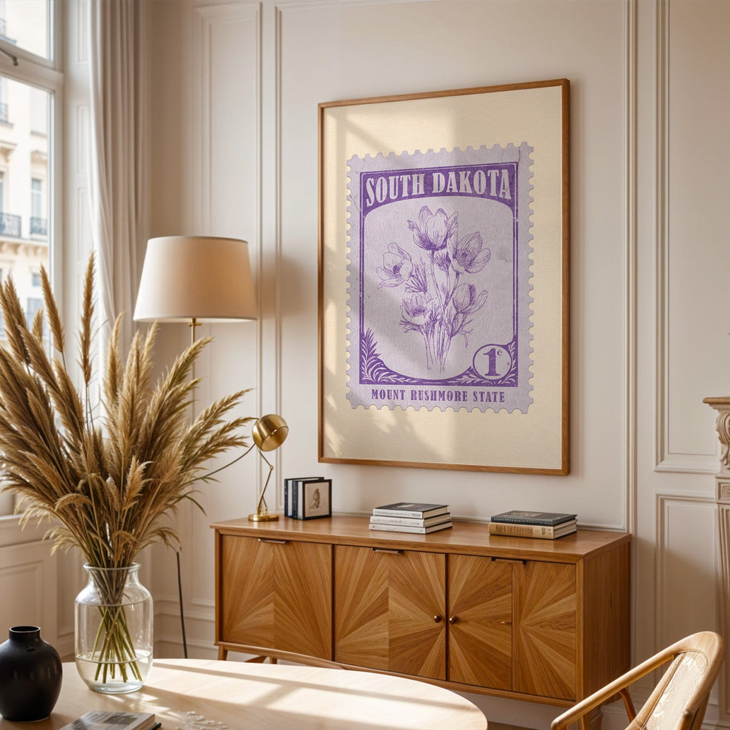 South Dakota stamp print framed above a wooden sideboard, pampas grass in a glass vase and a floor lamp