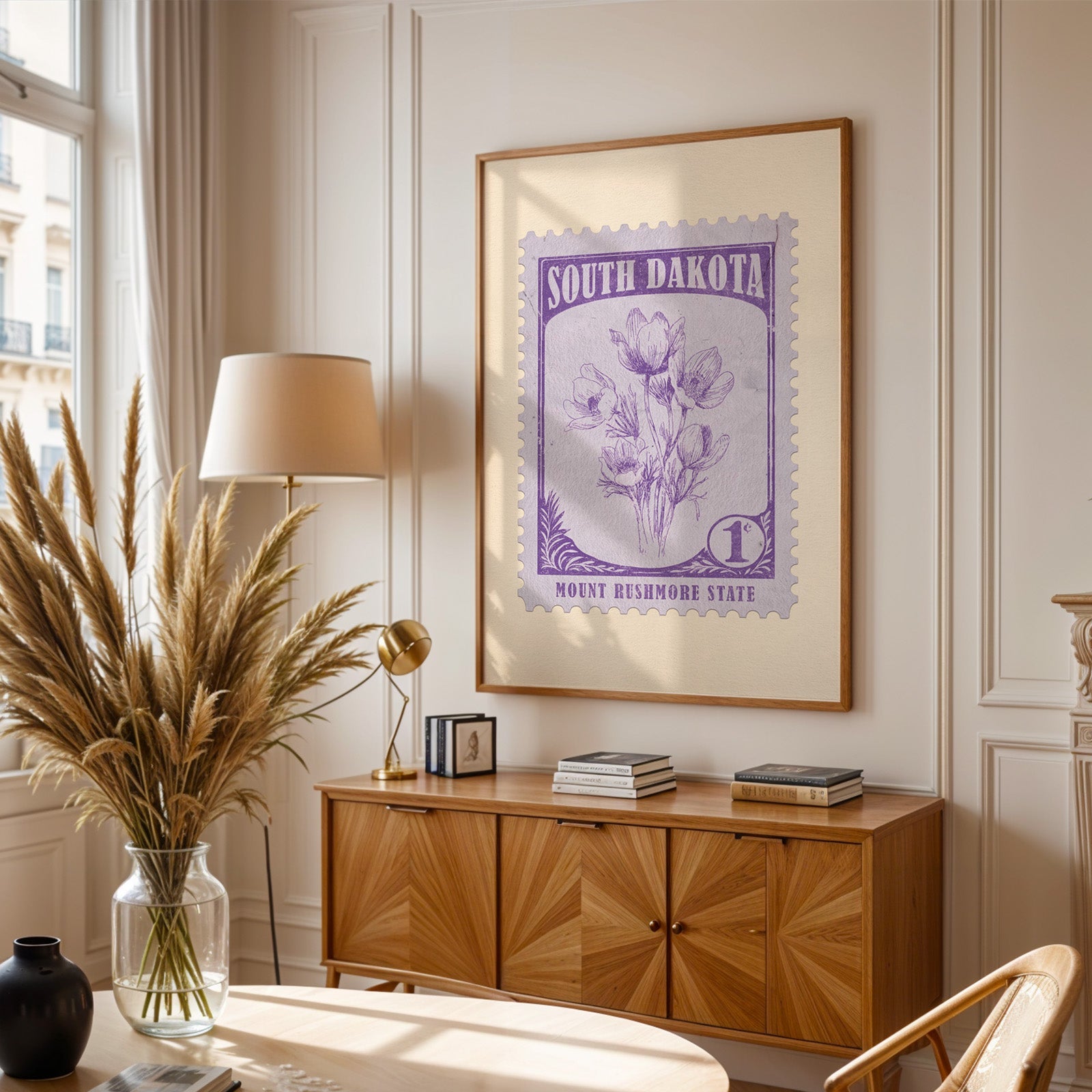 South Dakota stamp print framed above a wooden sideboard, pampas grass in a glass vase and a floor lamp