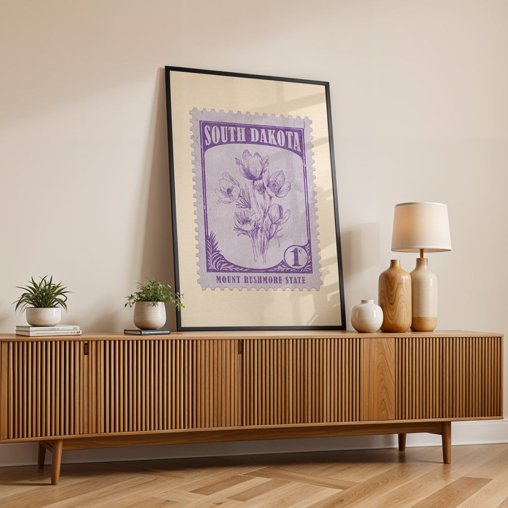 South Dakota state flower print in a black frame leaning on a fluted wood credenza with vases and a lamp