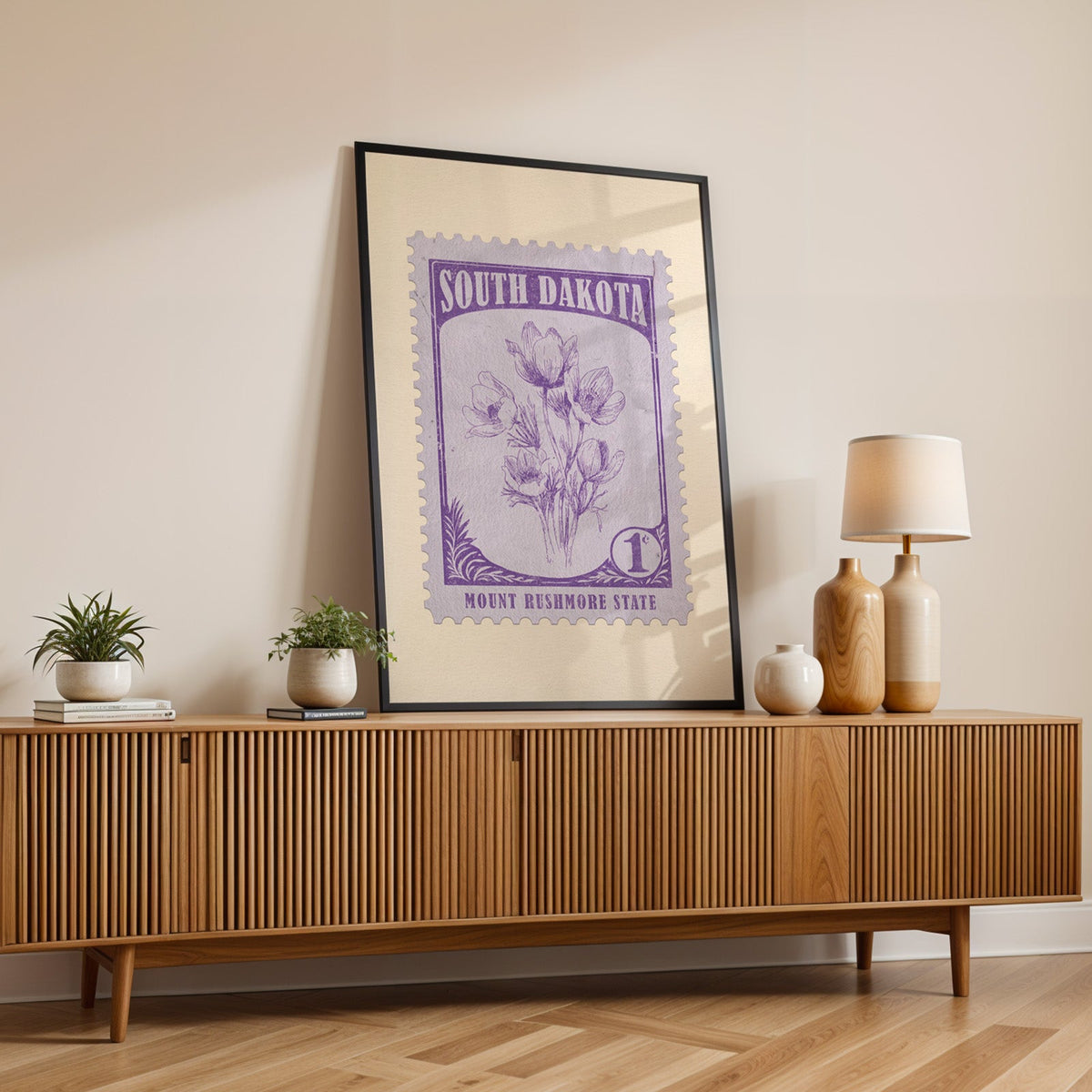 South Dakota state flower print in a black frame leaning on a fluted wood credenza with vases and a lamp