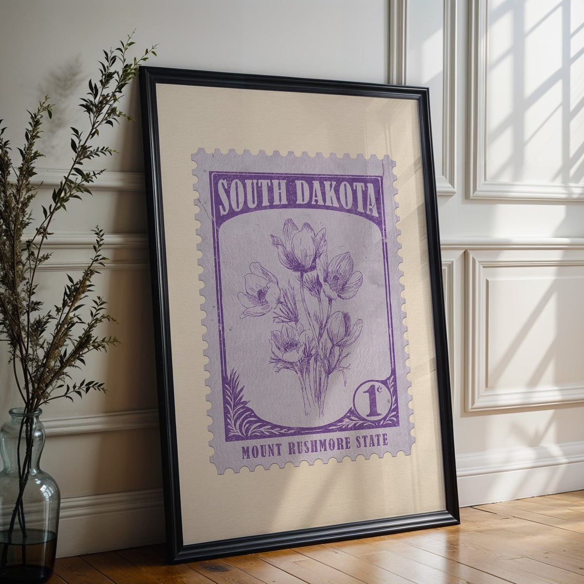 South Dakota state flower print in a black frame leaning on a white panelled wall beside olive branches