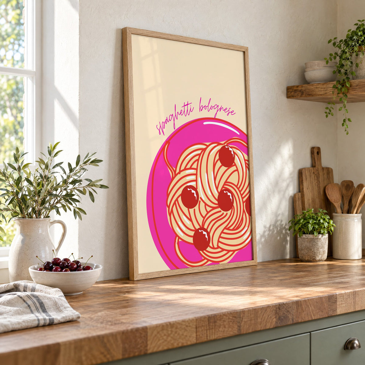 Spaghetti bolognese pink plate print in an oak frame leaning on a butcher block island beside a bowl of cherries